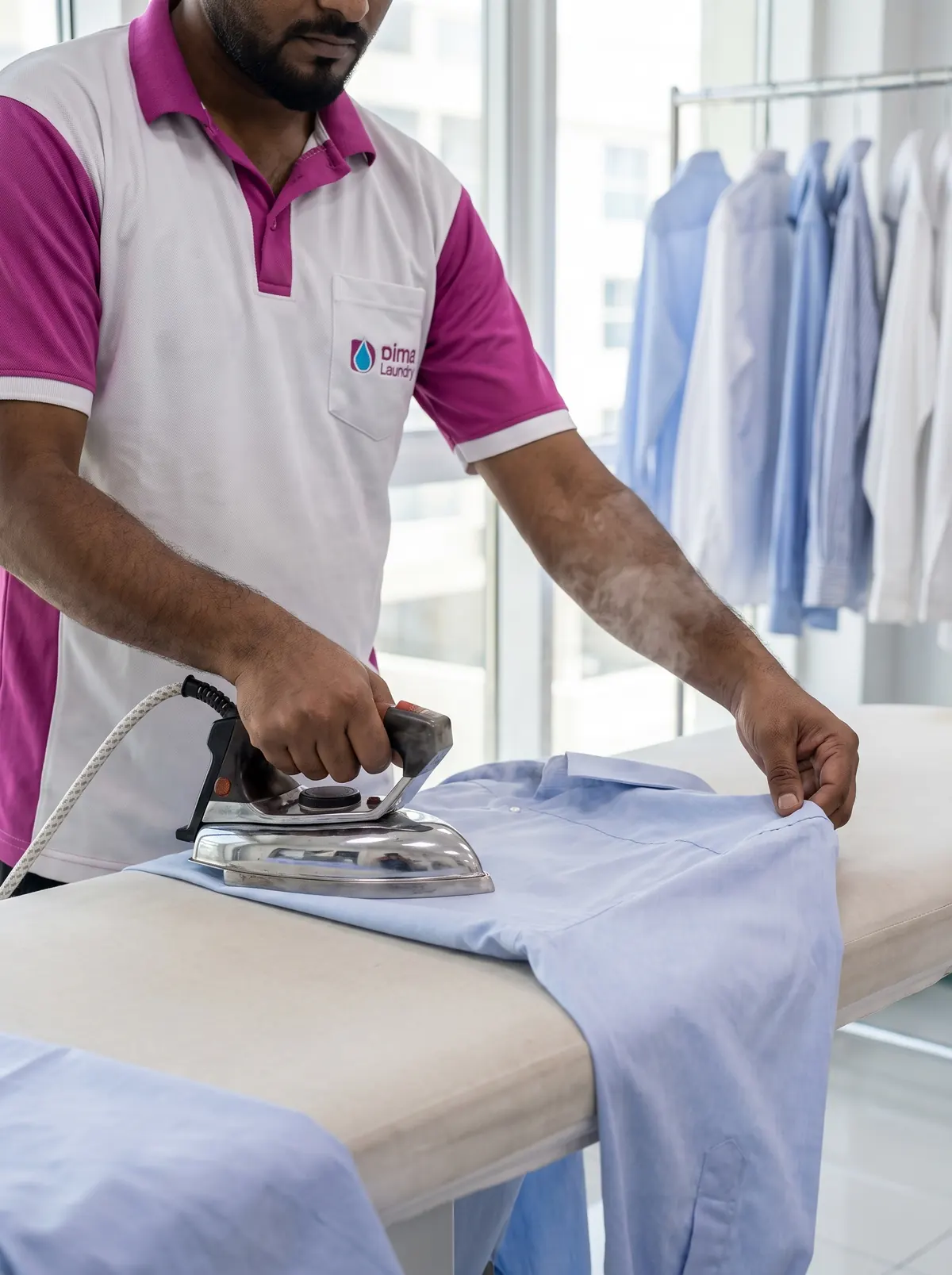 Dima Laundry team member pressing a shirt with a steam iron